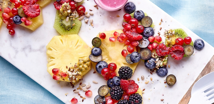 Salade de fruits au lait de coco, accompagnée de graines et d'une sauce aux baies