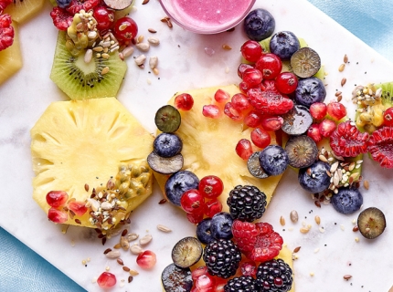 Salade de fruits au lait de coco, accompagnée de graines et d'une sauce aux baies