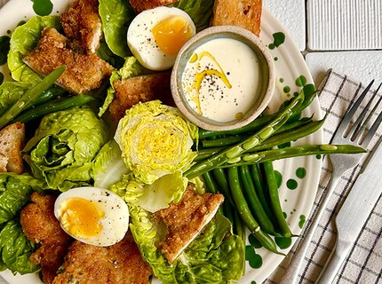 Salade César au veau pané, croûtons, œufs mollets et légumes verts